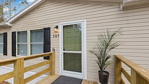 A wooden deck with a welcome mat, a green door, and a potted plant. - The Hideaway at Goose Pond Acres- Private Waterfront Retreat (Monticello)