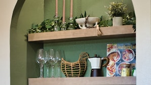 A kitchen with a wooden countertop, a coffee maker, and a shelf with glassware and a decorative bowl. - The Hideaway at Goose Pond Acres- Private Waterfront Retreat (Monticello)
