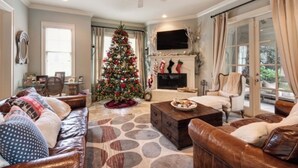 Ein Wohnzimmer mit Weihnachtsbaum, Ledersofas, Kamin und Fernseher.