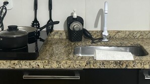 Une cuisine équipée d’un plan de travail en granit, d’une cuisinière, d’un évier et de divers ustensiles.