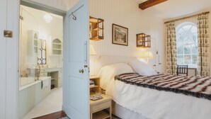 Ein Schlafzimmer mit einem Bett, Nachttisch, Lampe und einem Fenster mit Vorhängen.