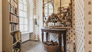 Eine Bibliothek mit Bücherregalen, einem großen Spiegel, einem Kamin und einem Wandpapier mit Muster.