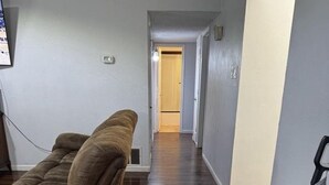 A hallway with a wooden floor, a brown sofa, and a vacuum cleaner. -  3-bedroom house in Arlington, 20 minutes from AT&T Stadium and the Stockyards. (Arlington)