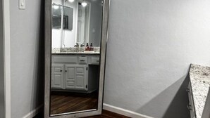 A corner room with a wooden floor, a large mirror, and a white wall. -  3-bedroom house in Arlington, 20 minutes from AT&T Stadium and the Stockyards. (Arlington)