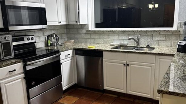A kitchen with white cabinets, a stainless steel dishwasher, a microwave, an oven, and a sink. -  3-bedroom house in Arlington, 20 minutes from AT&T Stadium and the Stockyards. (Arlington)