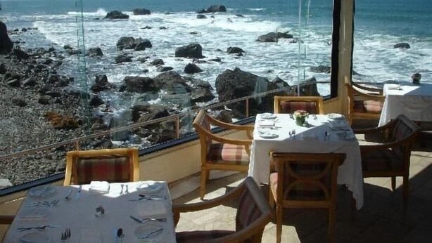 A restaurant with a view of the ocean and rocky shore, featuring tables and chairs. - Casa Raquel 12 ppl, 5 BD, prime location, steps from Coral y Marina gated com (Ensenada)