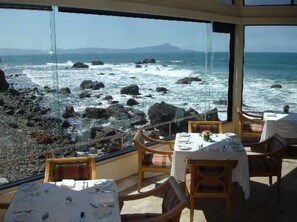 A restaurant with a view of the ocean and rocky shore, featuring tables and chairs. - Casa Raquel 12 ppl, 5 BD, prime location, steps from Coral y Marina gated com (Ensenada)