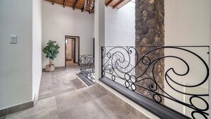 A hallway with a stone column, a potted plant, and a metal railing. - Casa Raquel 12 ppl, 5 BD, prime location, steps from Coral y Marina gated com (Ensenada)