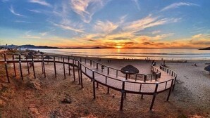 A beach with a wooden boardwalk, a sandy area, and a sunset in the background. - Casa Raquel 12 ppl, 5 BD, prime location, steps from Coral y Marina gated com (Ensenada)