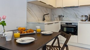 Eine moderne Küche mit Marmorarbeitsplatten, einem eingebauten Backofen und einem Essbereich mit Holztisch und Stühlen.