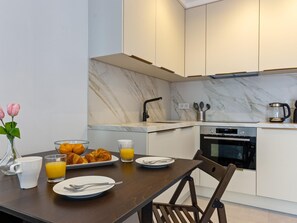 A modern kitchen with marble countertops, a built-in oven, and a dining area with a wooden table and chairs. - La Joya 1B. New apartment in Carihuela, 300 m from the beach (Torremolinos)