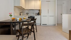 Eine moderne Küche mit weißen Schränken, einer Marmor-Spritzschutzwand und einem Essbereich mit einem dunklen Holztisch und Stühlen.