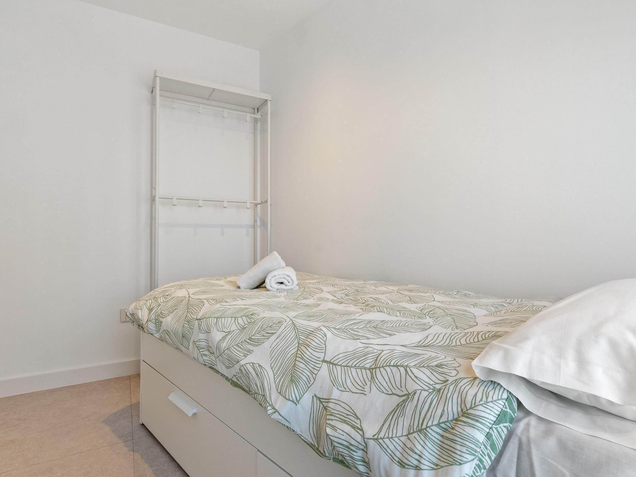 Quarto com cama, mesa de cabeceira, guarda-roupa e janela com persianas.