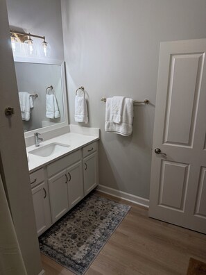 A bathroom with a white sink, mirror, and towel rack. - 2-bedroom/2-bath condo 1 mile walking trail from square and campus.  Sleeps 8-10 (Oxford)