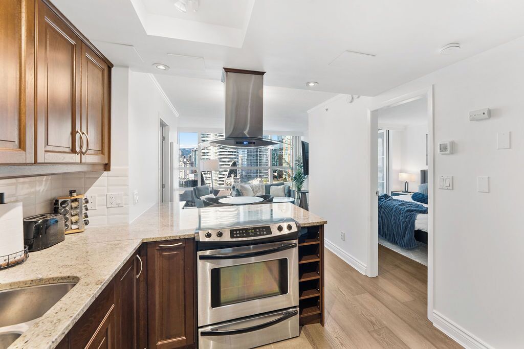 A modern kitchen with a central island, built-in oven, and a view of the city.