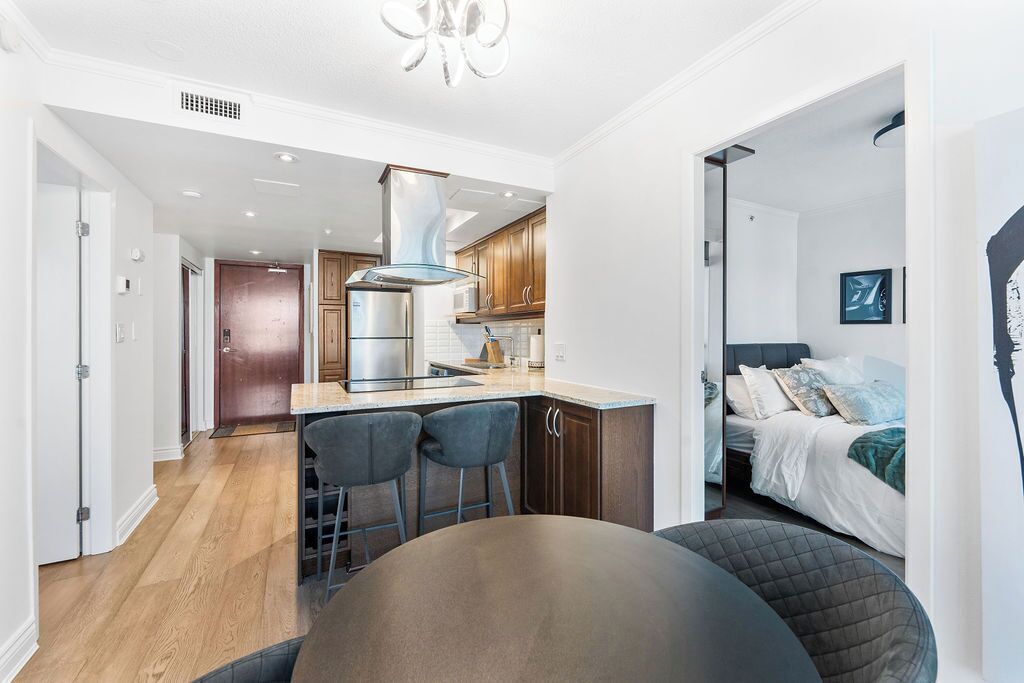 A modern kitchen with a central island, bar stools, and a dining table.