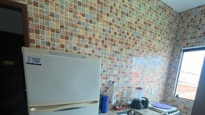 Une cuisine équipée d’un réfrigérateur, d’une cuisinière et d’un plan de travail recouvert de carreaux.