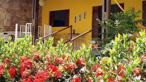 Un bâtiment jaune avec un toit en tuiles, des murs en pierre et un escalier menant à l’entrée.