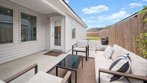 En overdækket terrasse med en sofa, stole og et sofabord.