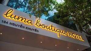 A hotel sign with illuminated text, a clear view of the address, and a tree in the background. - Luma Boutique Hotel (Hanoi)