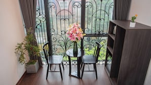 A balcony with a table, two chairs, a potted plant, and a vase with flowers. - Luma Boutique Hotel (Hanoi)