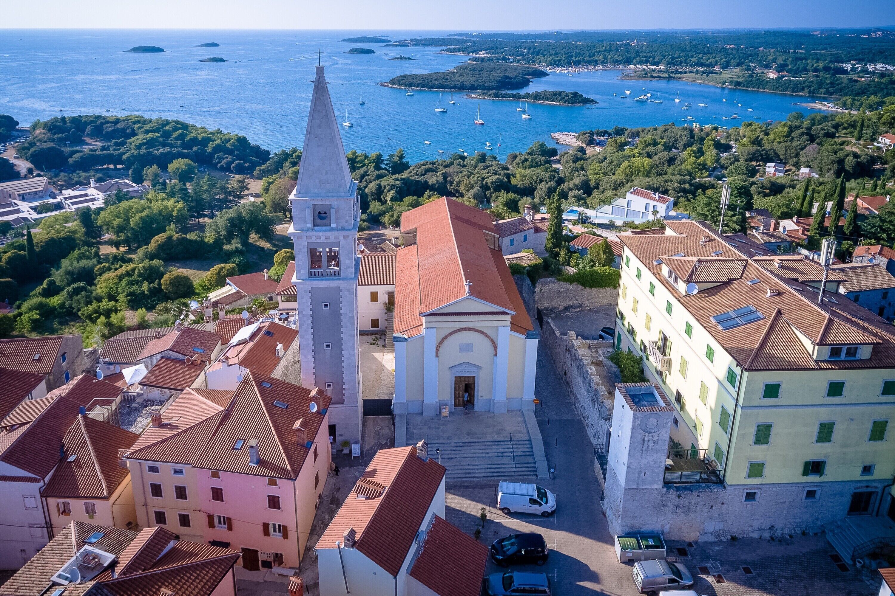 A coastal town with a prominent church, a narrow street, and boats in the background.