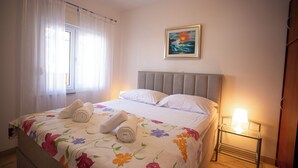 Un lit bien fait, avec une literie à motifs floraux, un tableau accroché au mur et une lampe de chevet.