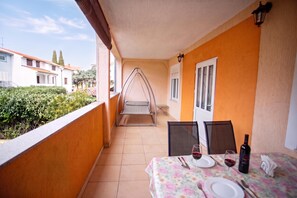 A balcony with a table set for two, a hanging chair, and a view of neighboring buildings. - Lovely Apartment Vrsar 6 With Balcony, Vrsar, Croatia (Vrsar)