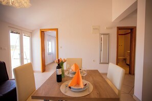 A dining area with a wooden table, chairs, and a bottle of wine. - Lovely Apartment Vrsar 2 With Balcony, Vrsar, Croatia (Vrsar)
