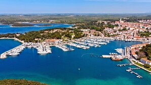 Vue aérienne d’une ville côtière avec un port de plaisance, des bateaux et des bâtiments.