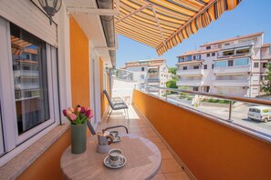Un balcon avec une table, des chaises, un vase de fleurs et une vue sur les bâtiments.