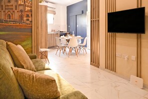 A modern living room with a sofa, a flat-screen TV mounted on the wall, and a dining area with a table and chairs. - Walk to Balluta & Spinola - modern 2bdr apart, St Julian's, Malta (St Julian's)
