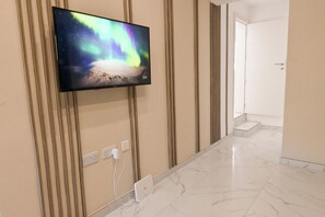 A flat-screen TV mounted on a wall with a view of the northern lights, a marble floor, and a door leading to another room. - Well Located Modern Apart Balluta Bay, St Julian's, Malta (St Julian's)