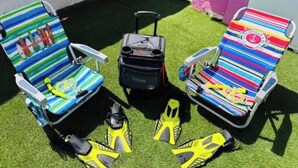 Deux fauteuils de jardin à rayures, une valise et du matériel de plongée en apnée, le tout posé sur du gazon synthétique.