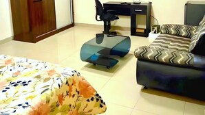 Ein Hotelzimmer mit einem Bett, einem Sofa, einem Schreibtisch mit Stuhl, einem Fernseher und einem Kleiderschrank.