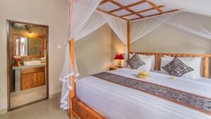 A bedroom with a canopy bed, a bedside table with a lamp, and a mirror. - D'junas Villas (Ubud)