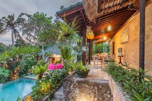 Un complexe hôtelier tropical doté d’une piscine, d’une végétation luxuriante et d’une structure en bois surmontée d’un toit de chaume.