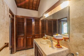 Une salle de bain avec une porte en bois, un lavabo, un miroir et un porte-serviettes.