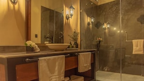 Ein Badezimmer mit großem Spiegel, Waschbecken, Dusche und Handtüchern.