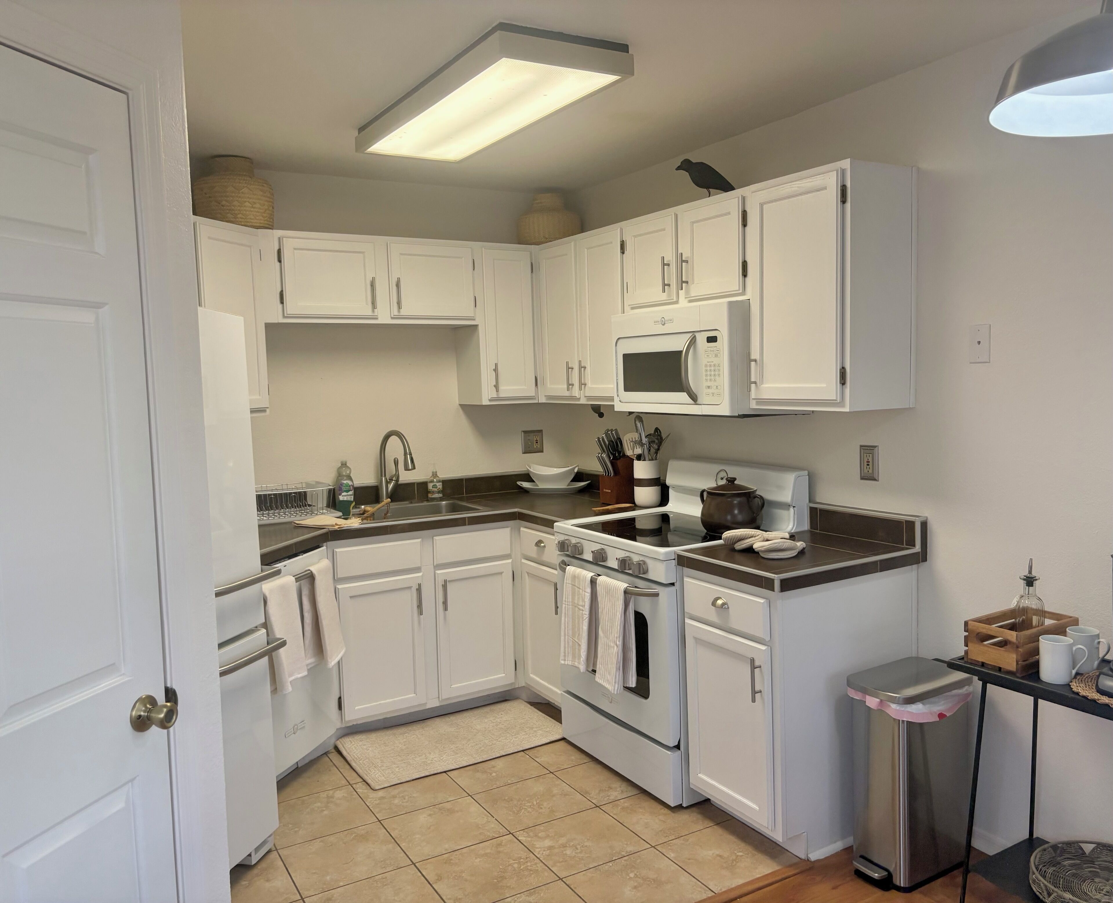 A kitchen with white cabinets, a microwave, a stove, and a sink.