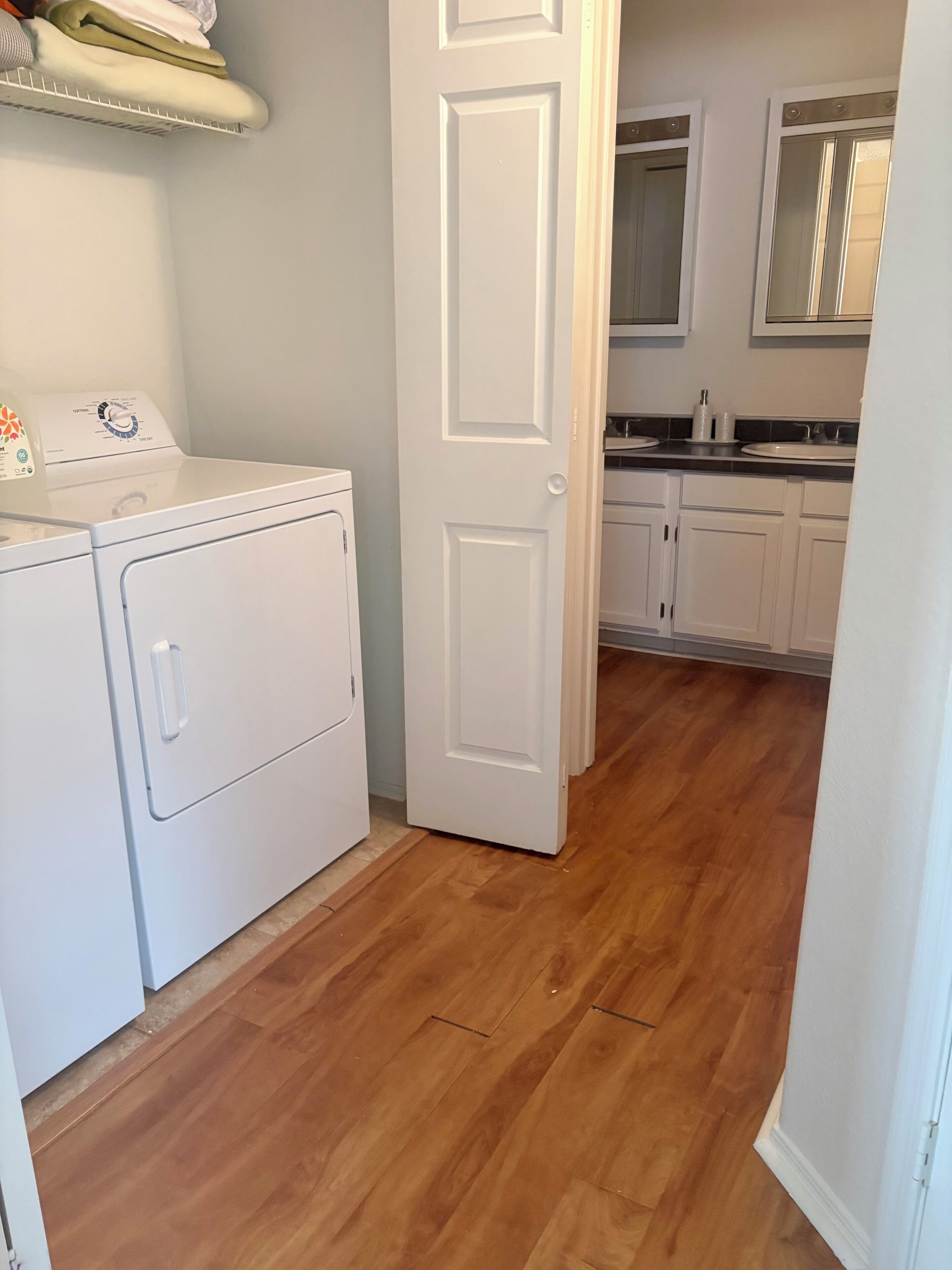 A laundry area with a washing machine, a door leading to a kitchen with a sink and cabinets.
