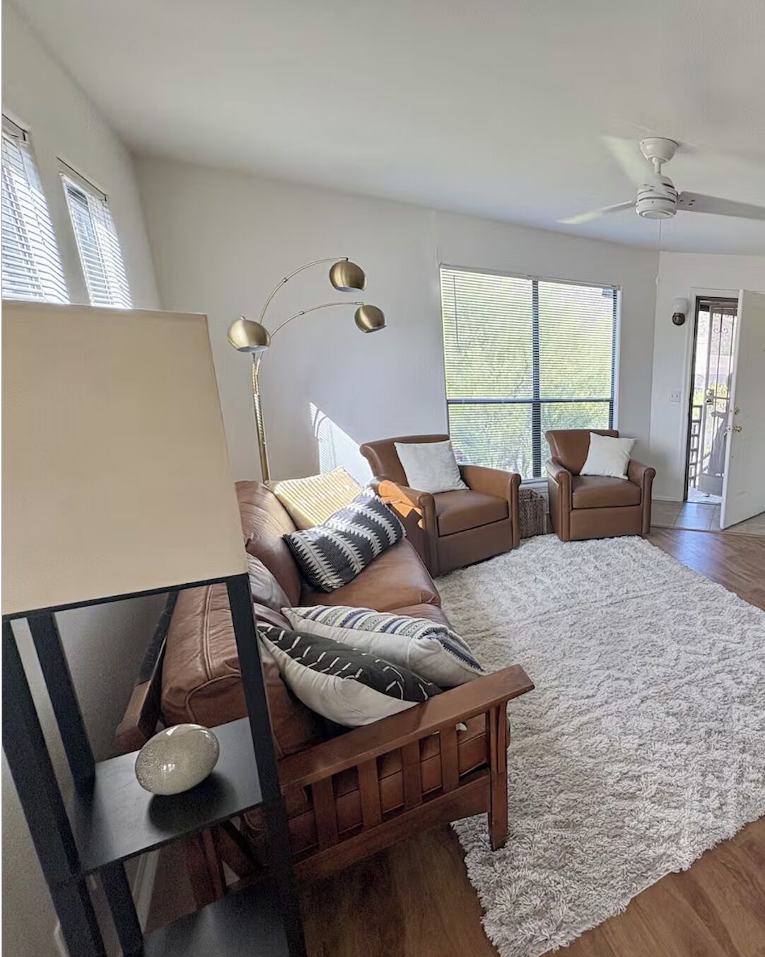 A modern living room with a sectional sofa, a coffee table, a floor lamp, and a large window providing natural light.