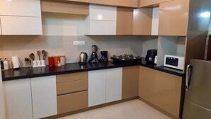 A modern kitchen with a black countertop, stainless steel appliances, and beige cabinetry. - Enjoyable 3-bedroom apartment with AC in vibrant Bengaluru (Bengaluru)