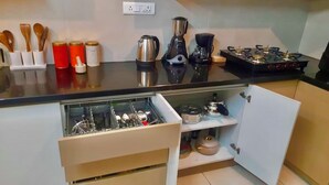 A kitchen with a black countertop, a coffee maker, a kettle, a blender, and a stove. - Enjoyable 3-bedroom apartment with AC in vibrant Bengaluru (Bengaluru)