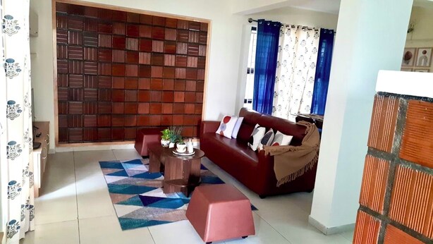 A living room with a sofa, a coffee table, and a patterned rug. - Enjoyable 3-bedroom apartment with AC in vibrant Bengaluru (Bengaluru)