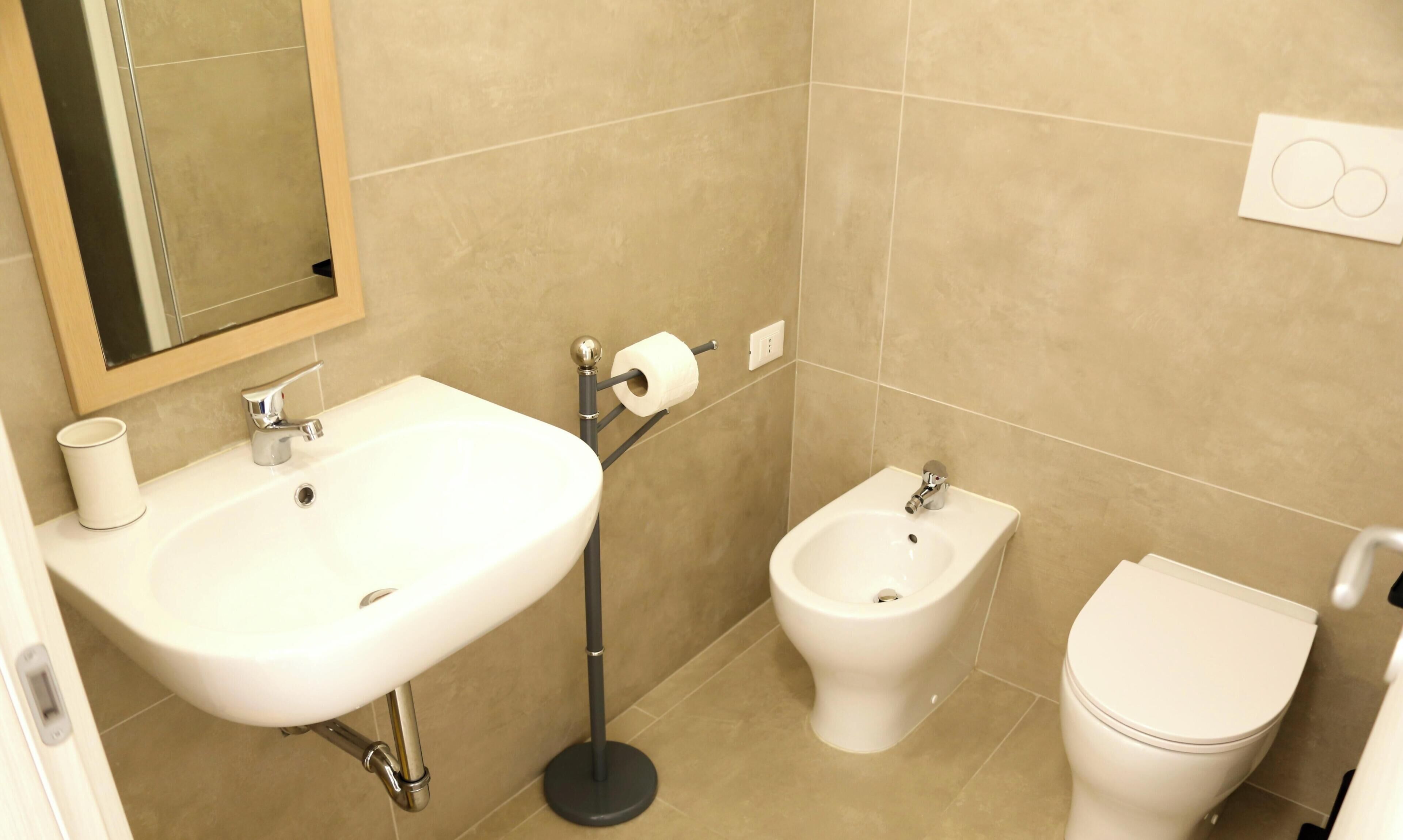 A bathroom with a sink, bidet, toilet, and a mirror.