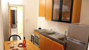 Una cocina funcional con gabinetes de madera, un refrigerador de acero inoxidable y una mesa de comedor con sillas.
