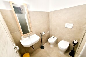 A bathroom with a sink, bidet, toilet, and mirror. - Duchessa Apartment in Downtown Gallipoli (Gallipoli)