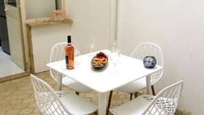 Ein weißer Tisch mit einer Flasche, einer Schüssel mit Essen und zwei Weingläsern.