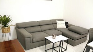 Ein graues Ecksofa mit einem Marmortisch und einer Topfpflanze.